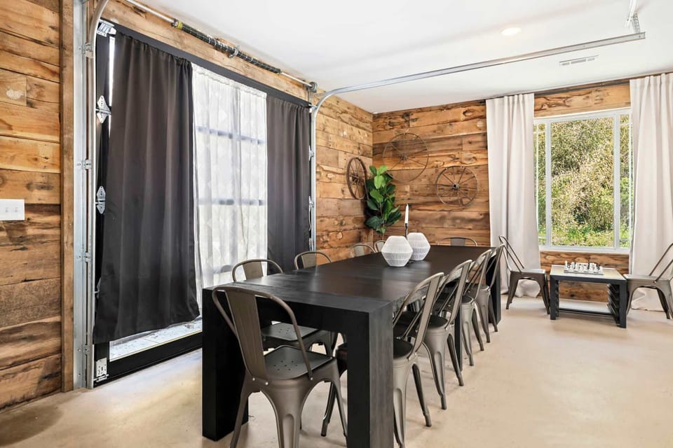 There's a long black rectangular dining table with seating for 10, complemented by three barstools at the kitchen island - perfect for shared meals and lively gatherings.