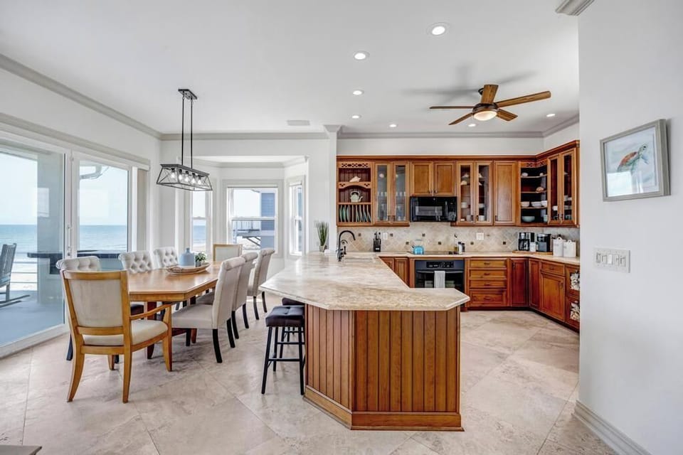 - Enjoy meals with stunning ocean views from the spacious dining area
- Open concept layout connects the gourmet kitchen and dining table seamlessly
- Smooth finishes, extra seating, and coastal light fill this breezy space