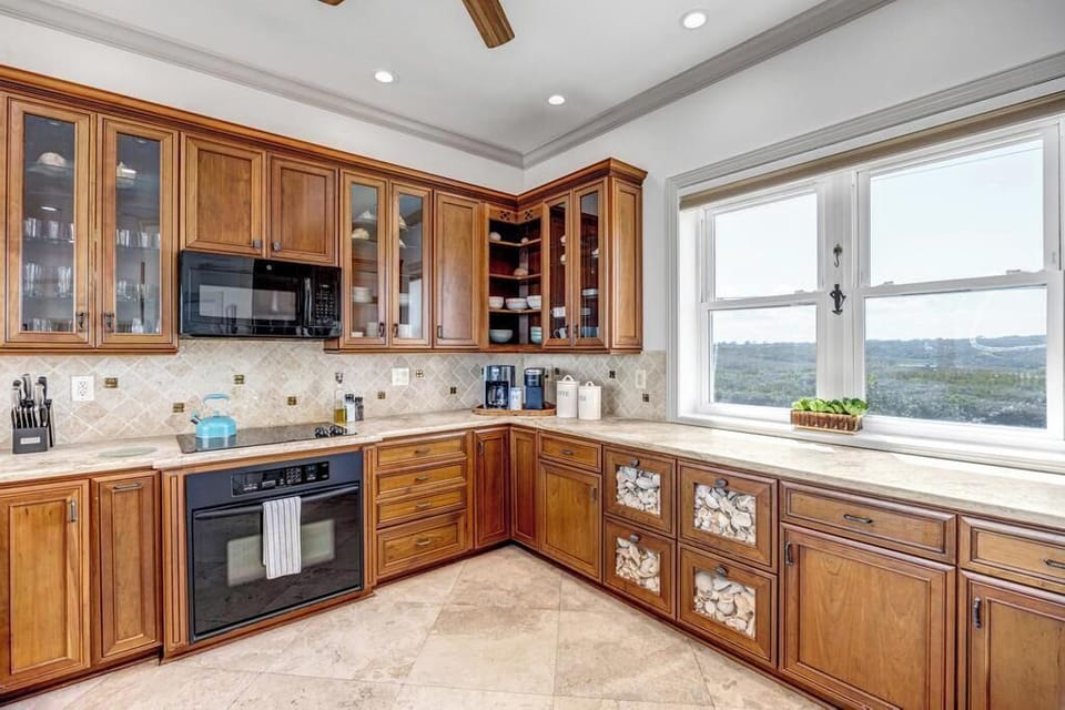 - Spacious countertops and tiled backsplash set a functional cooking scene
- Cabinetry with glass accents and built in oven complement classic design
- Large windows bring in natural light and showcase views of the coast