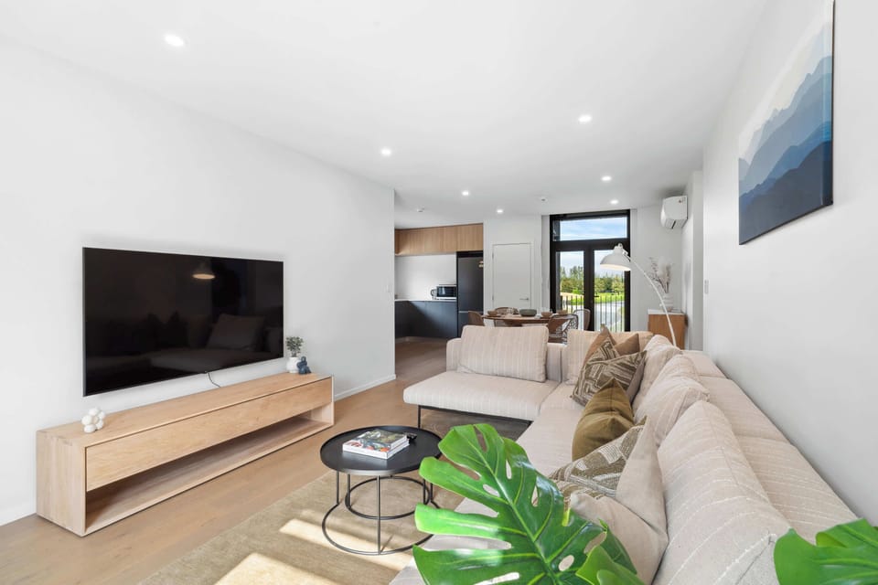 A stylish open-plan living space featuring a modern sectional sofa with earthy-toned cushions