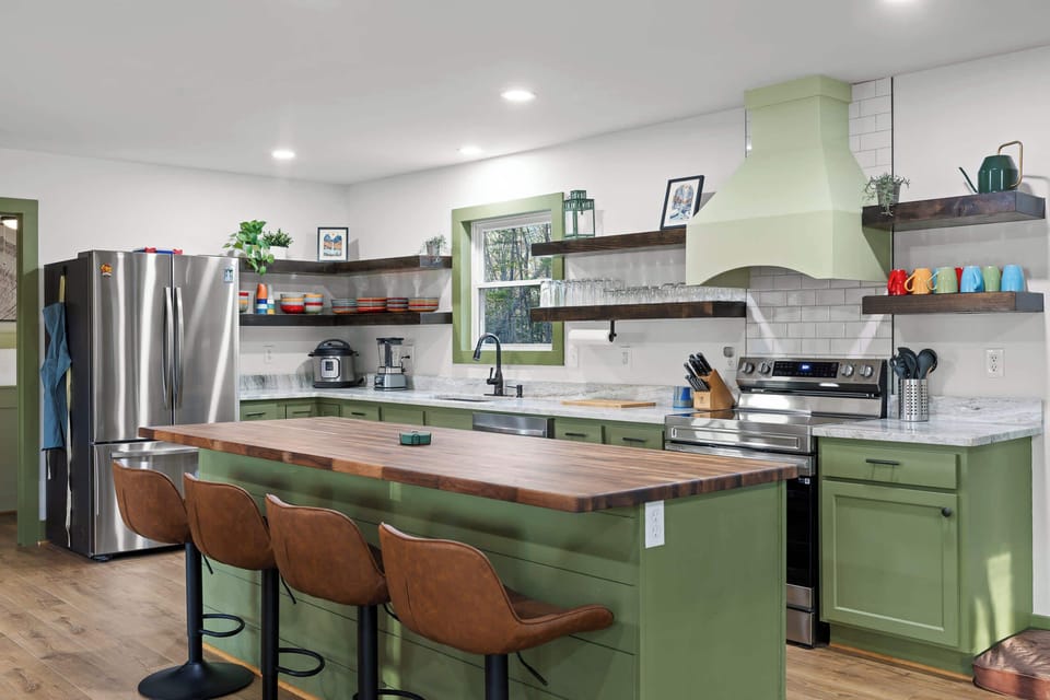 Fully stocked chef’s kitchen featuring stunning green cabinetry, modern appliances, and plenty of space for cooking and entertaining.