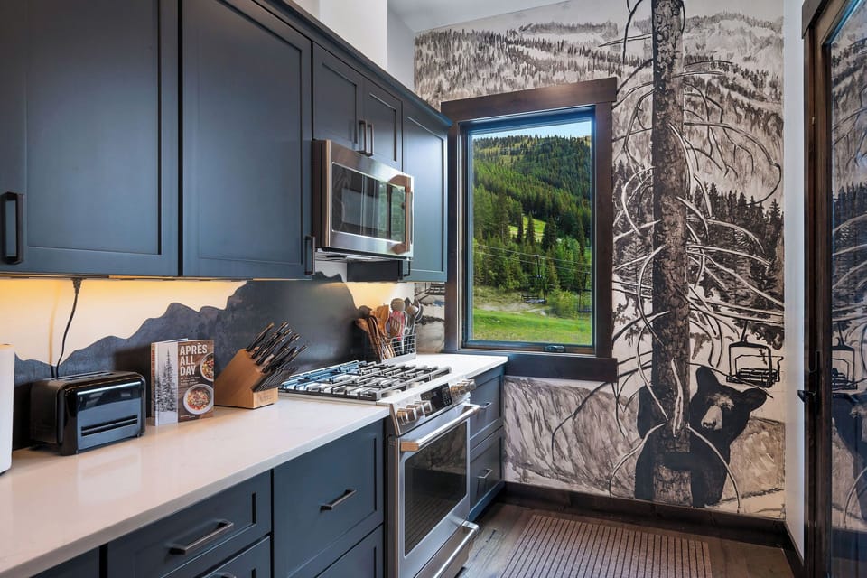 The bold mountain-inspired backsplash and hand-painted mural add a touch of unique artistry to the space. 