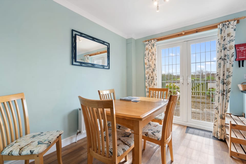Kitchen table and patio doors to rear patio at Kegyn Holiday Home Harlyn Bay, Padstow