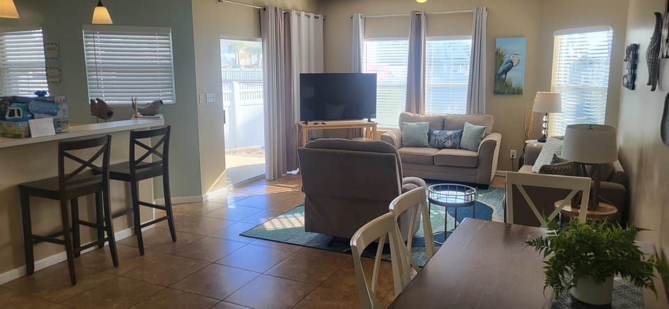 Open-concept living area filled with natural light, featuring comfortable seating, coastal décor. an