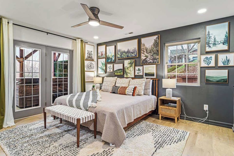 Bright bedroom w/ cozy bed, gallery wall art & French doors opening to the deck