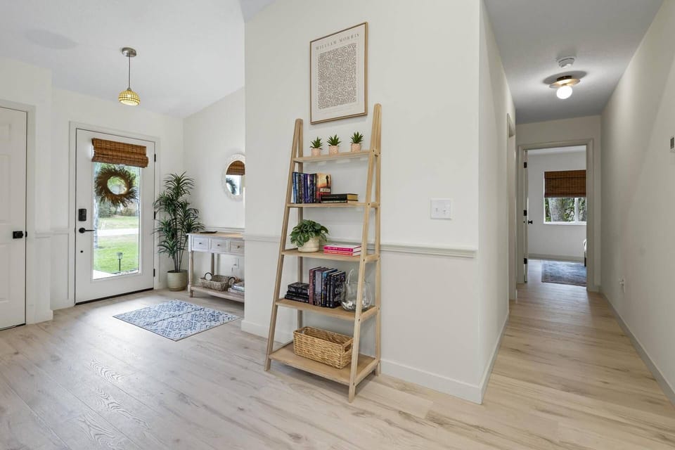 Bright and welcoming entryway opens to a spacious open-concept living area, with hallway access to guest bedrooms and shared bathroom.