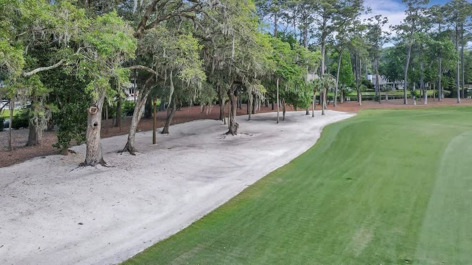 The property borders a beautifully manicured green, offering tranquil views of the fairway and natural sandy bunkers.