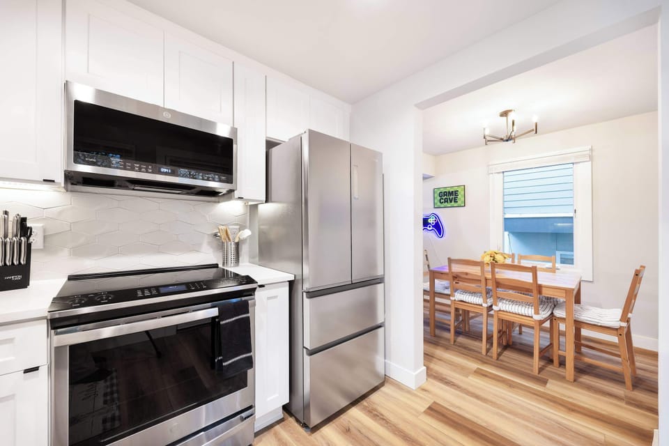 A sleek and fully equipped kitchen with stainless steel appliances, modern cabinetry, and a cozy dining table. Ideal for home-cooked meals or enjoying morning coffee in a beautifully designed space.