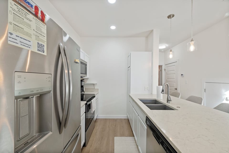 Your modern kitchen features sleek white cabinets, stainless steel appliances, and elegant pendant lighting for comfortable meal preparation.