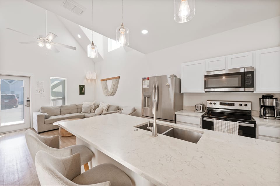 Relax in your bright, modern space with sleek kitchen island, cozy sectional, and soaring ceilings with stylish pendant lighting.