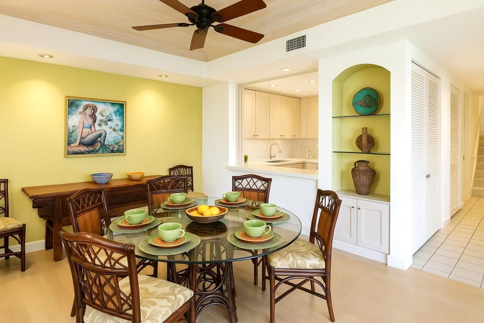The dining area features a sleek glass table and seating for four 