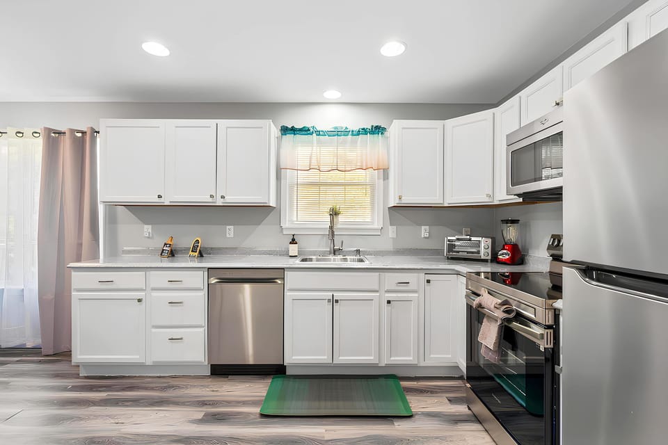 Fully equipped kitchen featuring a Frigidaire refrigerator, Samsung stove with baking sheets, Whirlpool microwave, Midea dishwasher, blender, toaster oven, and a fire extinguisher for safety.