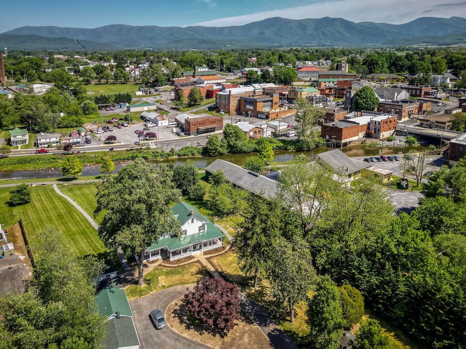 Aerial view of a small town with a river and mountain backdrop showcasing a peaceful rural setting.