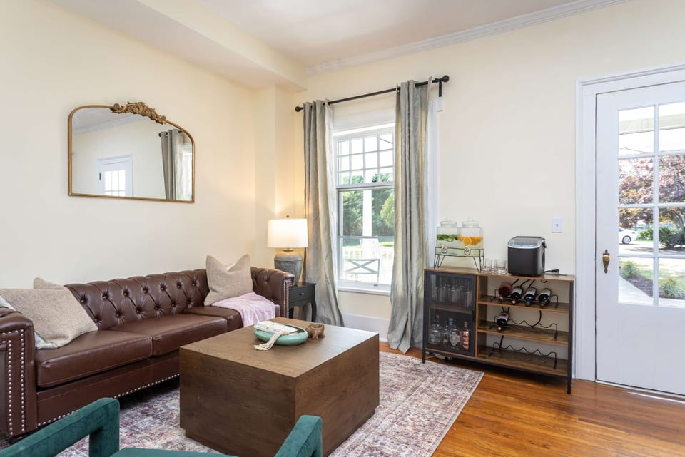 Cozy living room with a leather sofa, natural light, and a wine storage cabinet.