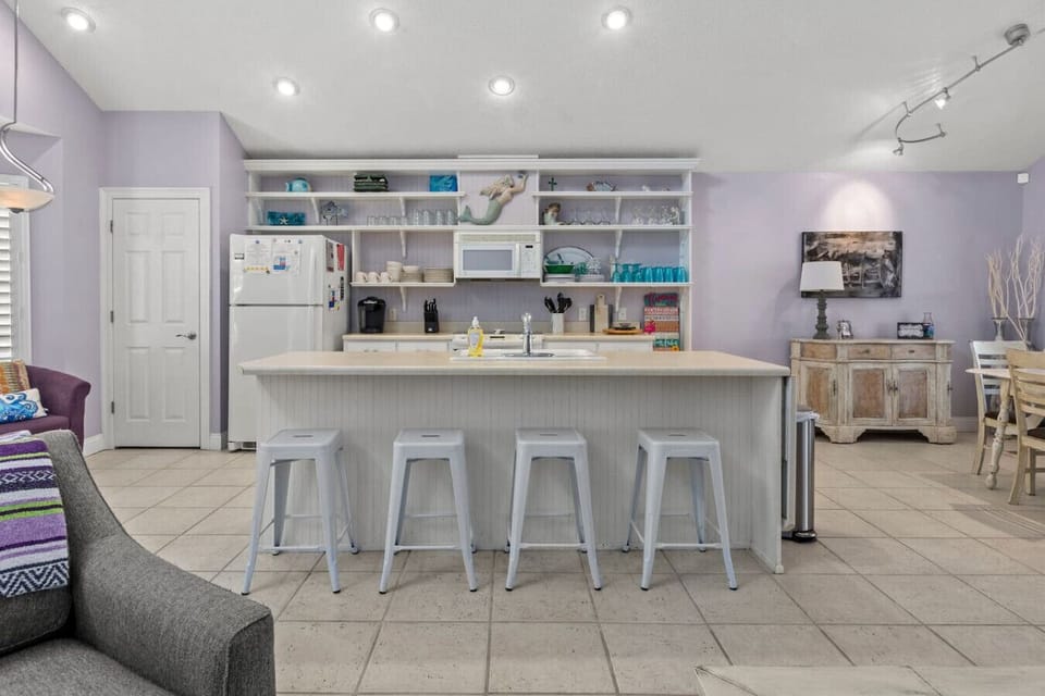 A spacious kitchen features a sleek island with four high chairs, creating a perfect spot for casual meals or chatting while cooking. The open layout offers plenty of room to move around and enjoy both cooking and entertaining.