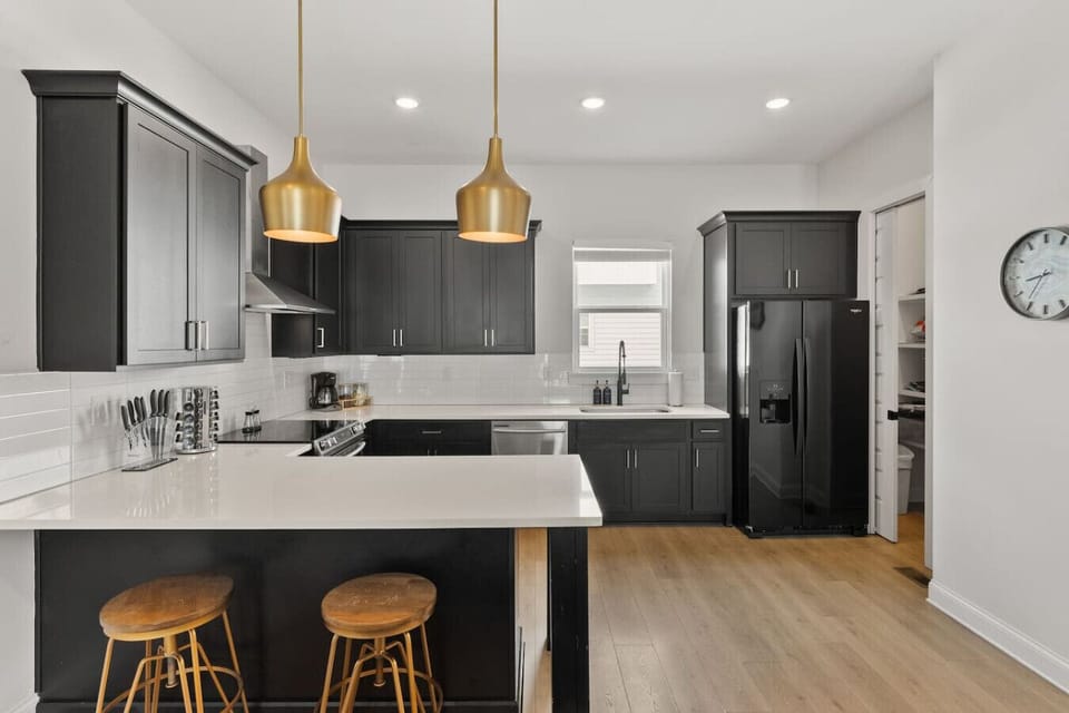 Fully-equipped kitchen with stainless steel appliances, a coffee maker + grounds provided, and all the dishware + utensils you might need to cook and enjoy a meal at home. Seating for two at the kitchen counter.