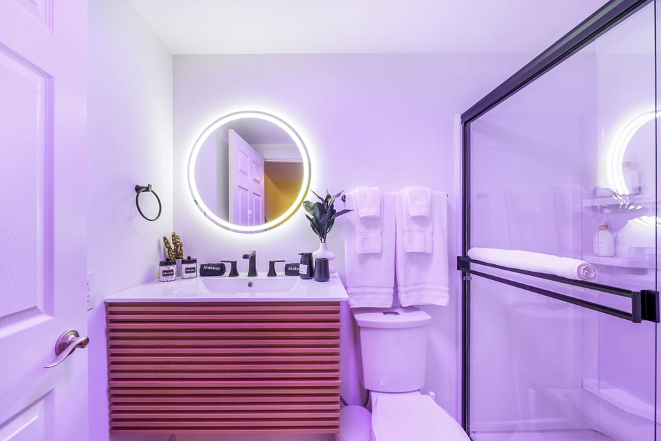 Step into your luxurious bathroom featuring a stunning LED backlit mirror and rainfall shower with premium amenities awaiting your arrival.