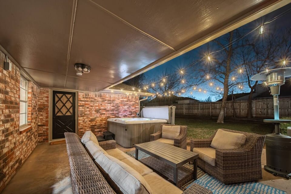 Transform your evenings in this private backyard retreat—complete with a bubbling hot tub, stylish wicker seating, twinkling string lights, and a covered patio. Perfect for entertaining or unwinding under the stars in a peaceful home.