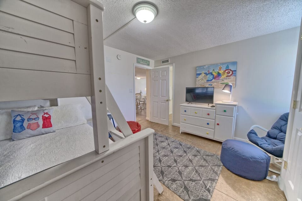 A colorful, comfy bunk room with a TV and space to lounge or play.
