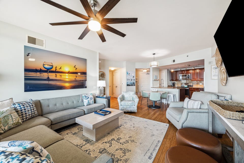 Elegant and inviting living area with contemporary coastal accents, wood flooring, and seamless flow to a stylish kitchen and dining space.