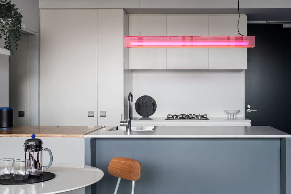 Cook in style in this sleek, modern kitchen featuring high-end appliances, minimalist cabinetry, and a vibrant designer light fixture that adds a pop of personality