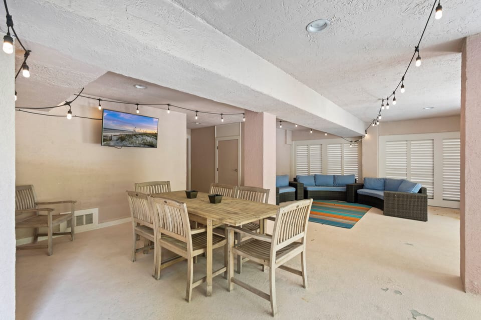 The poolside covered patio invites you to lounge on plush furniture while catching up on a favorite TV show.