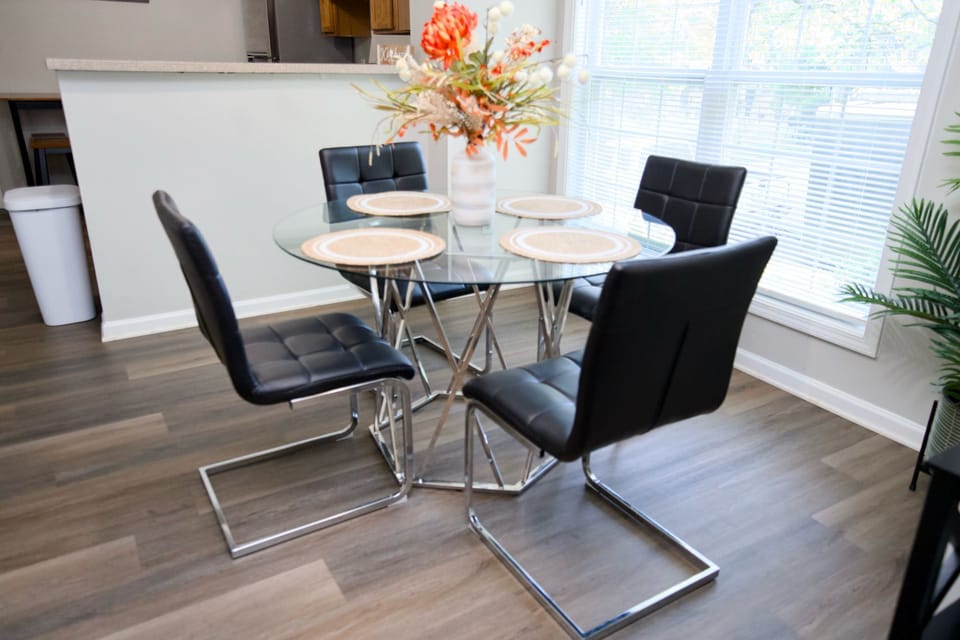 Enjoy meals in a stylish dining area featuring a glass-top table wth chairs 