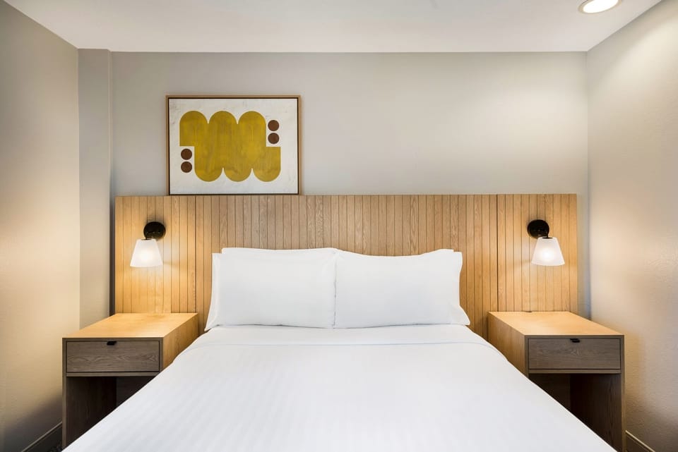 Drift off in a calm, cozy bed with glowing sconces.
