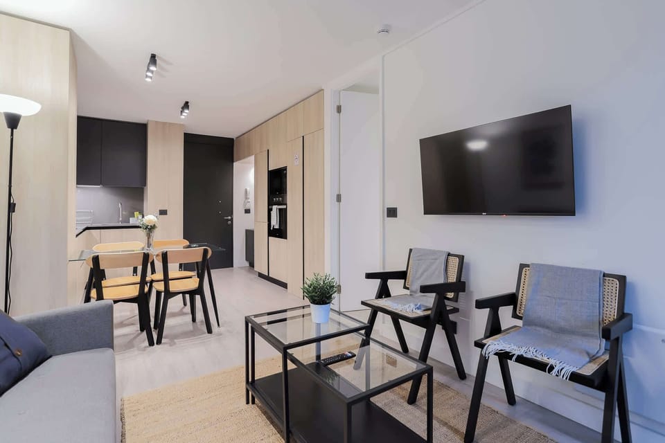 Chic and modern living space with sleek furnishings and a cozy dining area, perfect for relaxing or entertaining.