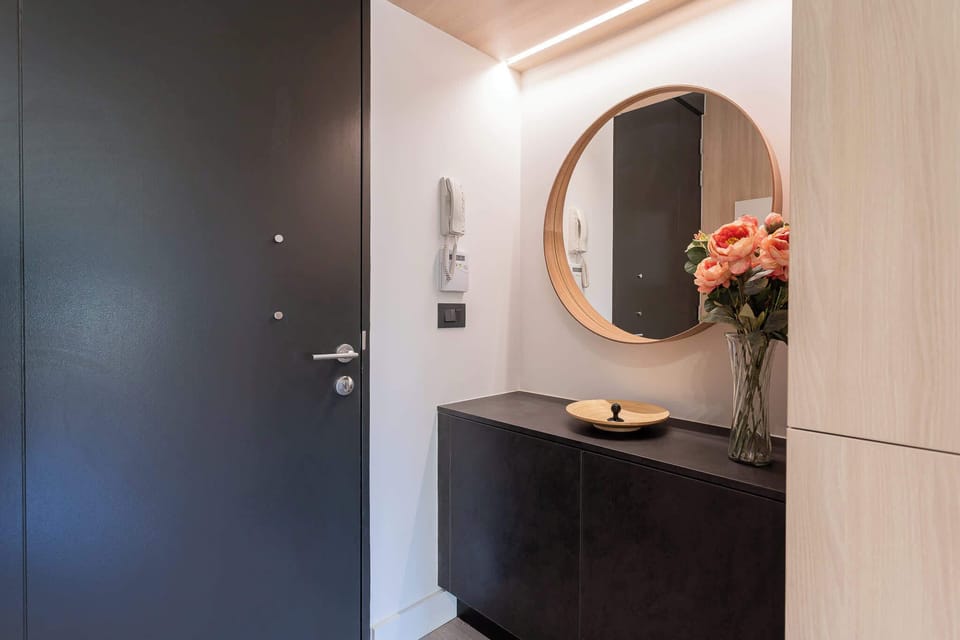 Step into a modern entryway with elegant decor, featuring a stylish mirror and fresh flowers for a warm welcome.