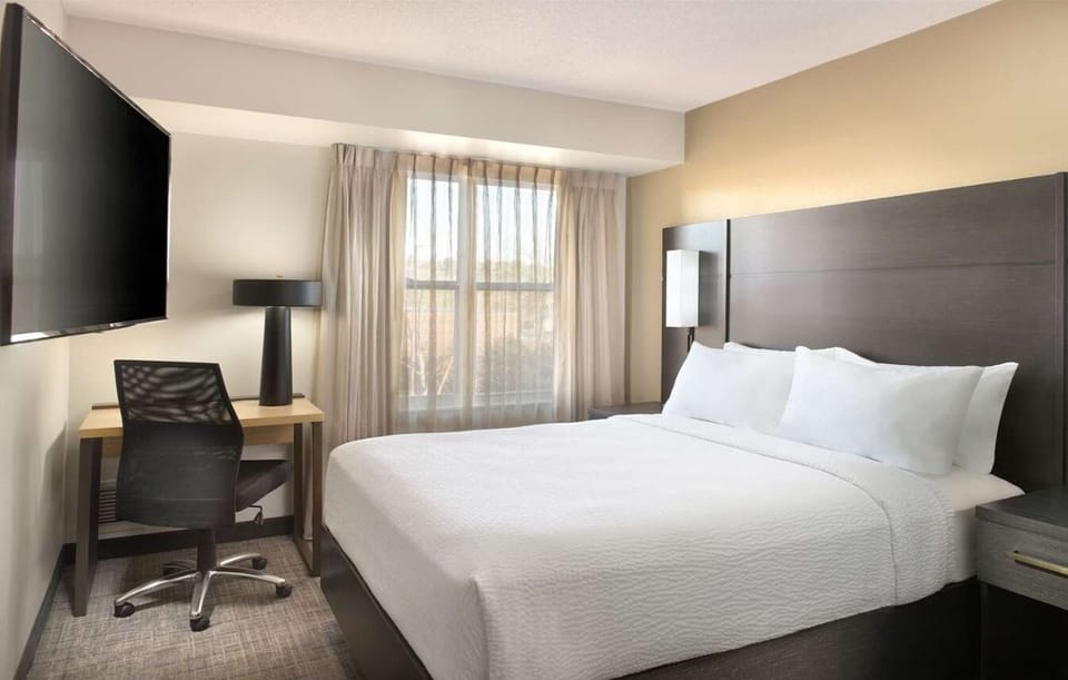 Unwind in crisp bedding beside sunlit windows and workspace.