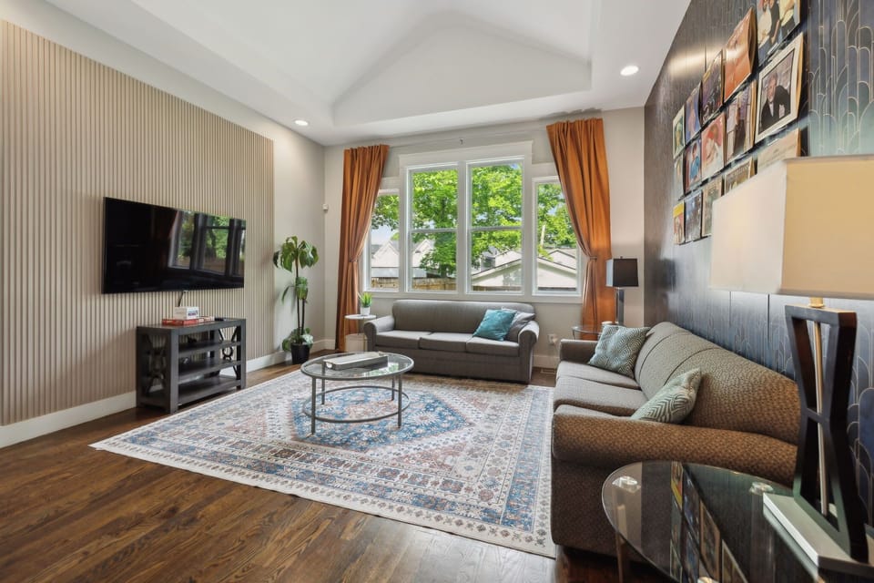 Living Room: Unit B - Golden drapes, plush seating, and a sleek TV console create a warm, modern vibe. A perfect place to relax or entertain.