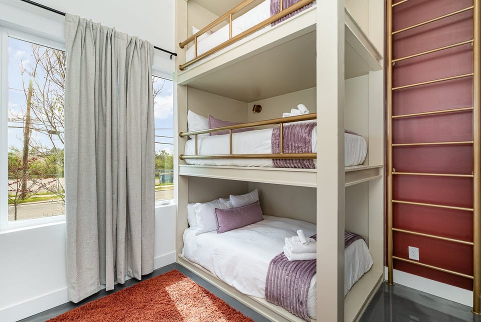 Unit 1: 4th bedroom with 3 Full beds (bunk bed style), smart TV, vanity, and suite bathroom. (1st Floor)