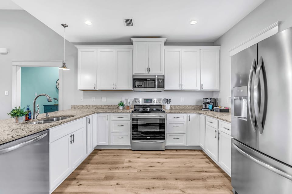 Spacious open kitchen w/ stainless steel appliances, well stocked to make meals.