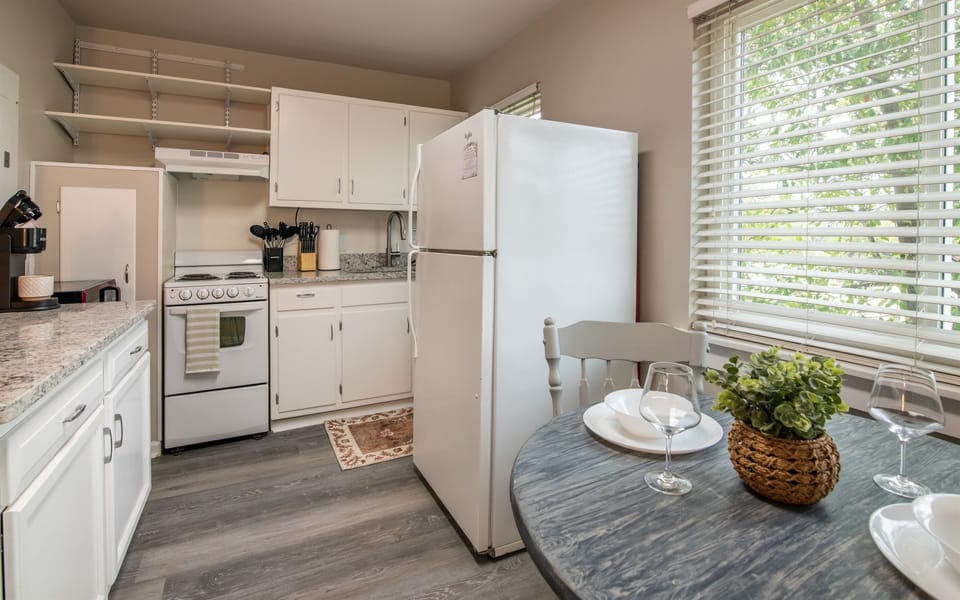  Kitchen and dining area with natural light, white cabinetry, and full-sized fridge — ideal for extended stays.
