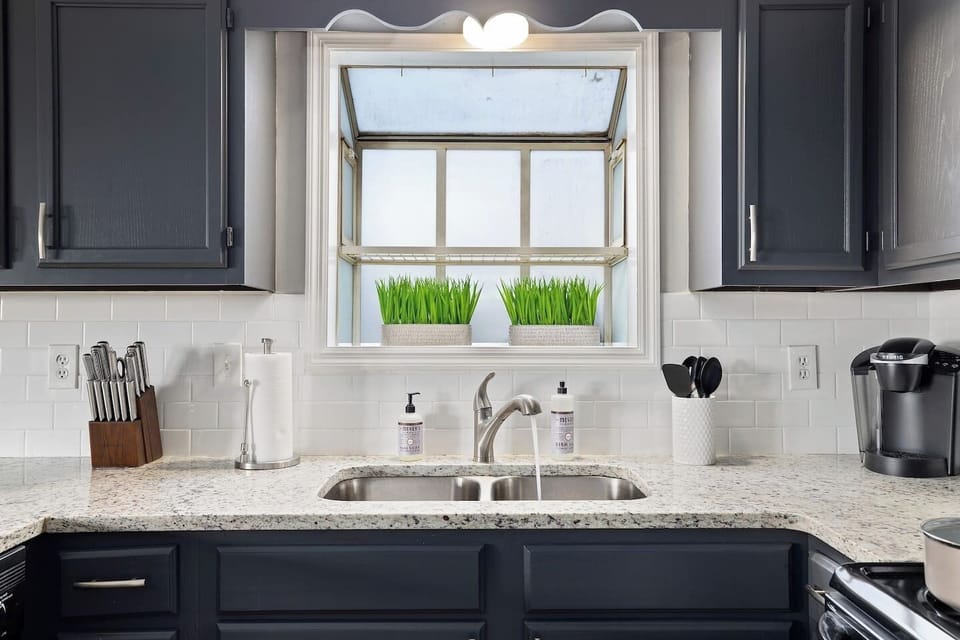 Bright kitchen sink area with granite countertops, stainless fixtures, and modern cabinets.
