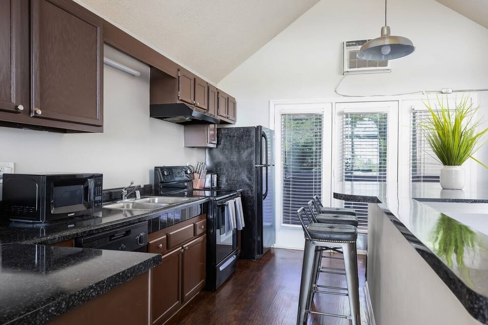 Modern kitchen with dark cabinets, black appliances, and bar seating for casual dining.