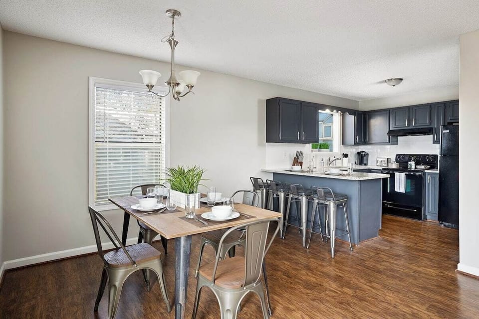 Welcome to Unit F at Hilltop Hideaway! This inviting dining and kitchen space showcases a cozy table for four, modern appliances, and a bright, open layout—perfect for starting your Birmingham getaway!