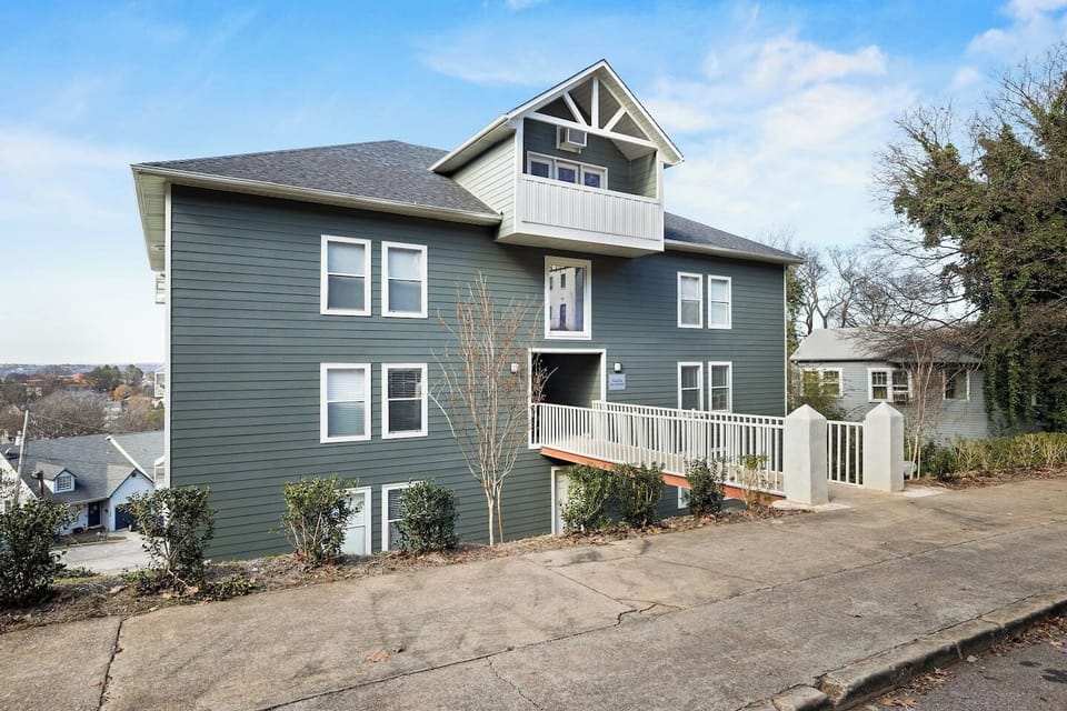 Exterior of Hilltop Hideaway, a stylish multi-unit building with a modern green facade and a welcoming entrance.