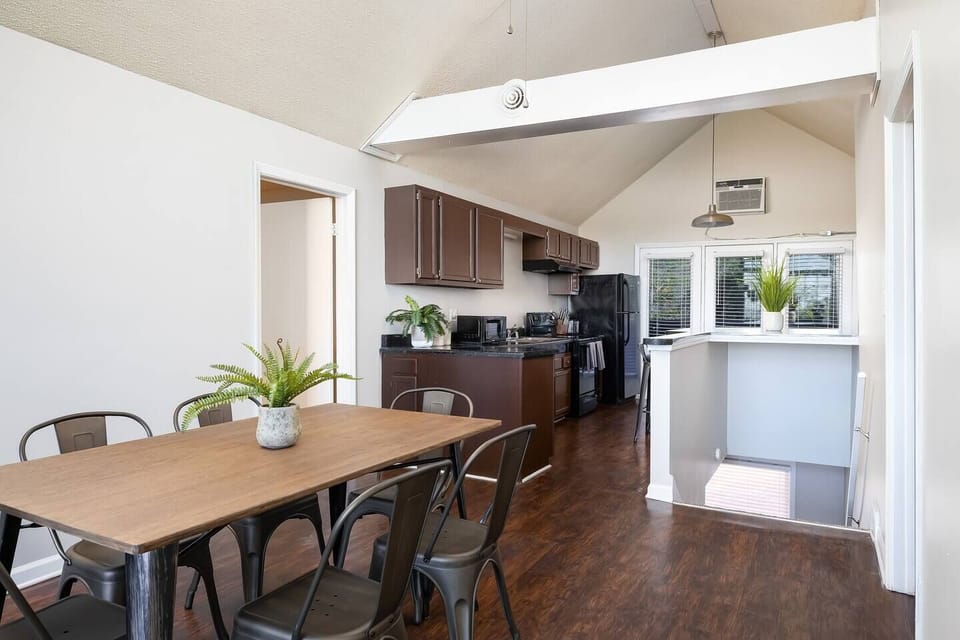 Open dining area with a modern table, ample seating, and a fully equipped kitchen in view.