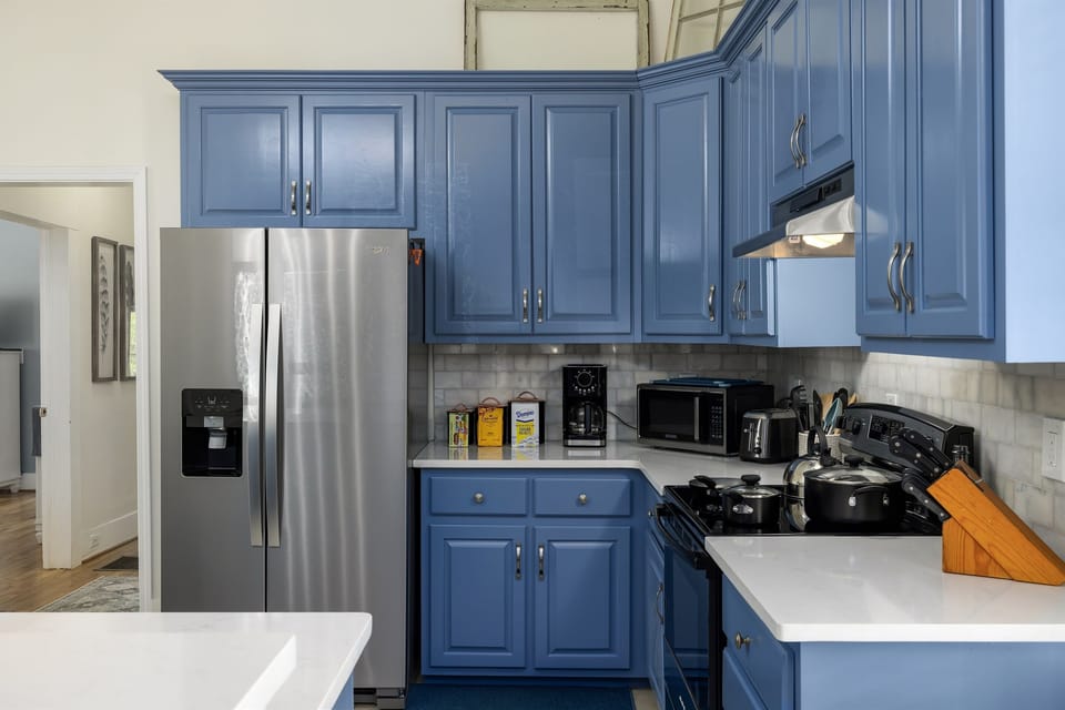he kitchen stands out with its vibrant blue cabinets, creating a cheerful and contemporary atmosphere. The modern appliances and ample counter space make it both functional and stylish.