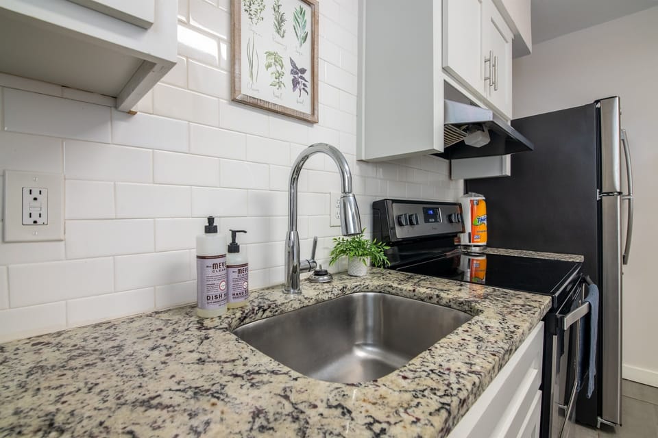 Sleek and simple kitchen sink area with modern finishes and under-cabinet lighting.