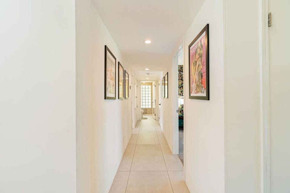 Long hallway w/ framed art, soft lighting, & a calm, airy feel throughout.