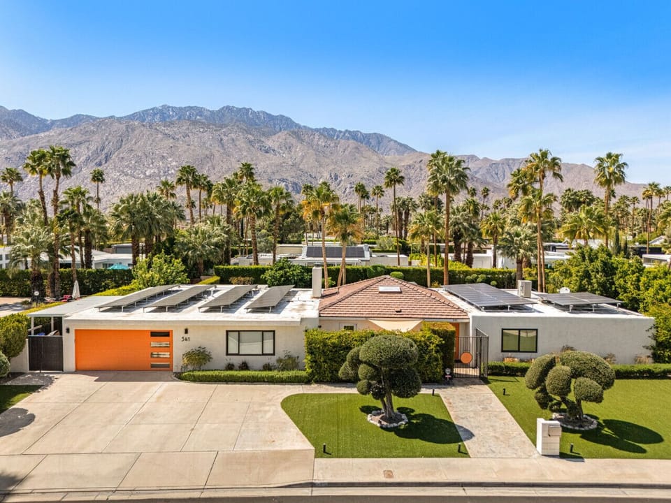 Aerial view highlighting the home’s layout w/ pool, palms, & mountains beyond.