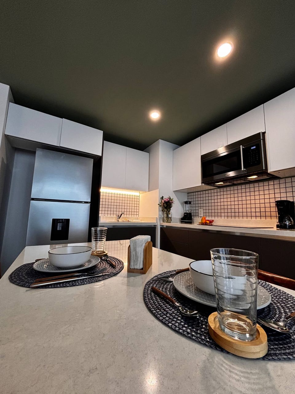 Kitchen equipped with utensils, electric stove and large refrigerator.