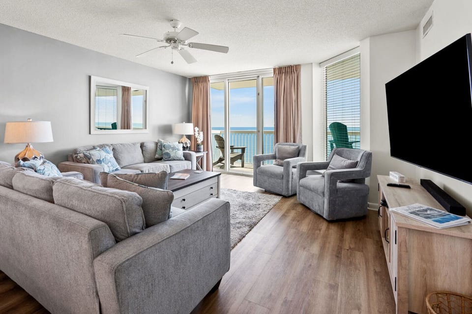 Living area with two armchairs, a ceiling fan and ocean views at Paradise Pointe 9E in Cherry Grove
