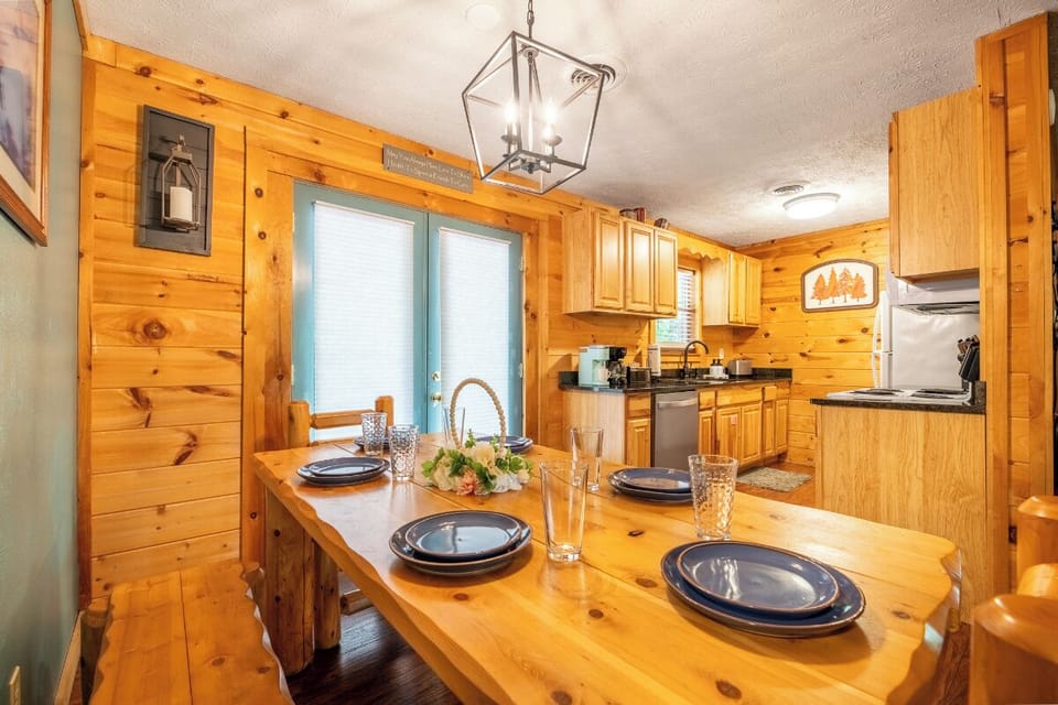 Gather around your private dining table in this warm, pine-clad kitchen—sunlight streams in as you savor meals together in rustic comfort.