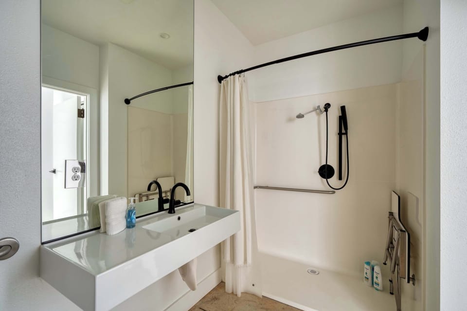Bathroom with a rectangular sink and shower with grab bars.