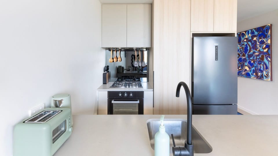 Sleek kitchen with full appliances and clean, minimalist design.