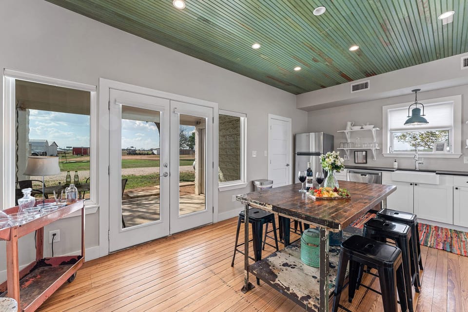 Gather around the island as golden-hour light filters through the French doors. It’s where food meets conversation, all framed by the colors of the Texas evening sky just beyond.